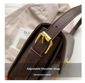 Detail of brown leather bag showing adjustable shoulder strap with gold metal buckle