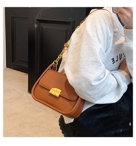 Detail of a brown leather shoulder bag featuring a square gold metal buckle and chain strap