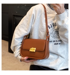Close-up of caramel leather mini square crossbody bag with gold metallic buckle and strap