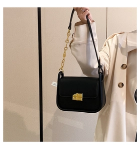Detail of black pebbled leather mini bag with gold geometric buckle and chain strap