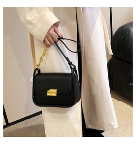 Close-up of elegant black leather handbag featuring a stylish gold clasp and chain