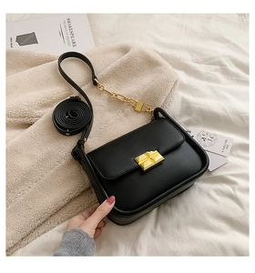 Detail shot of black leather mini square bag with golden turn-lock and chain strap