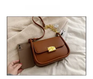 Close-up of brown pebble leather mini bag with gold hardware next to a smartphone