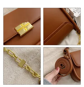 Detail of brown leather handbag featuring golden geometric clasp and chain strap