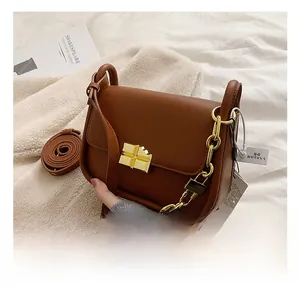 Detailed close-up of brown matte leather handbag with vintage gold cross lock