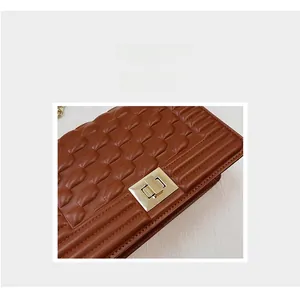 Gros plan sur le cuir matelassé marron et le fermoir rotatif en métal doré du sac
