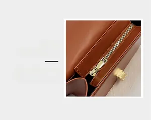 Détail de la fermeture éclair et du fermoir doré sur le sac à bandoulière en cuir marron