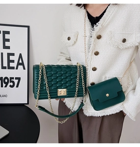 Détail du sac bandoulière tissé vert foncé et du petit sac croisé avec chaînes dorées