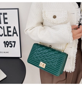 Détail d'un sac bandoulière matelassé vert foncé avec chaîne dorée et fermoir rotatif
