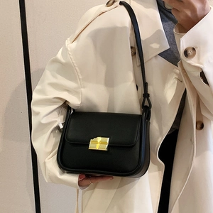 Classic black leather crossbody mini bag with elegant gold metal buckle on model