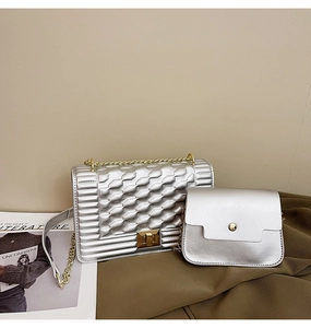 Détail du sac à bandoulière argenté avec chaîne, fermoir doré et petite pochette assortie