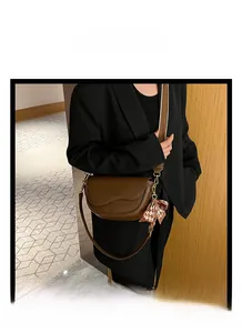 Detail of dark brown saddle bag featuring a stylish bow and textured wide strap