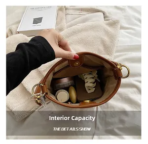 Macro view of the spacious internal capacity showing daily essentials in a brown bucket bag