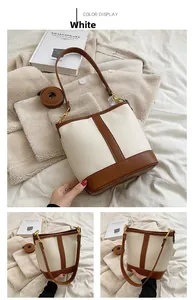 Detail view of white pebbled leather bucket bag with brown trim and gold hardware