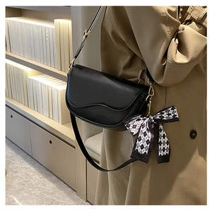 Detail of black saddle bag with wavy flap and checkered bow on trench coat model