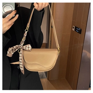Detail of light brown saddle bag with textured leather and checkered silk scarf accent