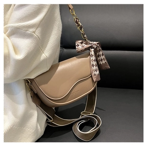 Detail of light brown saddle bag with checkered silk scarf and wide woven shoulder strap