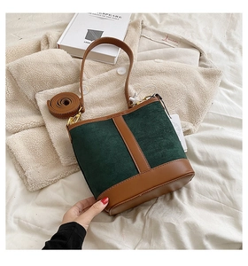 Close-up of green suede bucket bag with brown leather trim and golden metal hardware