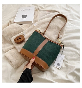 Detail of vintage patchwork bucket bag showing dark green suede and brown leather texture