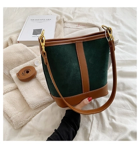 Detail of dark green suede bucket bag with brown leather trim and golden metal hooks