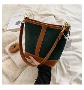 Detail of the vintage emerald green suede and dark brown leather bucket bag with gold ring