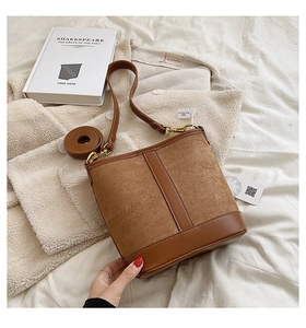 Detail of a brown patchwork bucket bag featuring suede texture and smooth leather strap