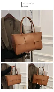 Detail of a brown woven tote bag featuring large cross-weave texture and sturdy handles
