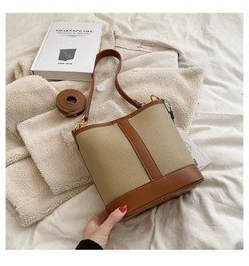 Close-up of beige and brown leather bucket bag with pebble texture and metal hook