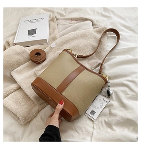 Detail view of contrast color bucket bag with pebbled texture and spare shoulder strap