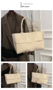 Detail of off-white woven tote bag featuring large grid texture and dual handles