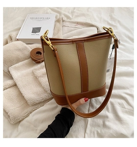 Detailed macro view of the coffee and beige textured leather on the bucket bag
