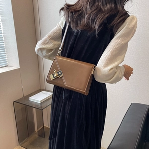 Brown faux leather crossbody bag featuring unique geometric flap and gold metal charm detail