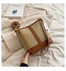Detail of beige and brown bucket bag with lychee texture leather and contrast stitching