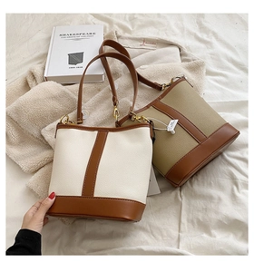 Close-up of contrast stitching on vintage bucket bags in cream and khaki faux leather