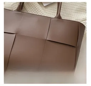 Detail of dark brown woven tote bag featuring high-quality lychee textured synthetic leather
