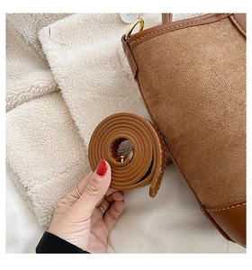 Detail of brown suede shoulder bag showing smooth leather trim and golden metal clasp