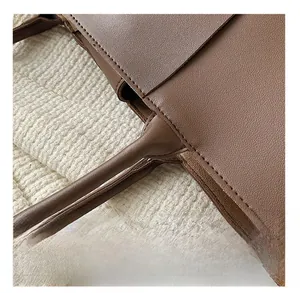 Close-up of brown woven leather bag handle with precise stitching and grainy texture
