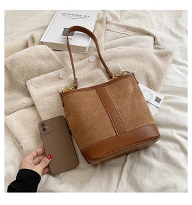 Brown patchwork bucket bag with gold hardware shown next to a phone for size scale