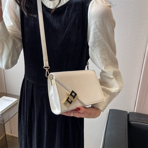 Detail of cream white leather crossbody bag featuring an elegant black-gold metal buckle
