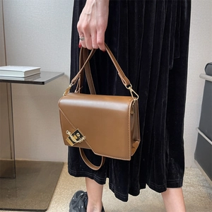 Detail of vintage brown leather handbag with asymmetrical flap and gold metal hardware