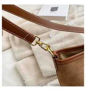 Detail of brown shoulder bag with contrast stitching and golden hardware buckle