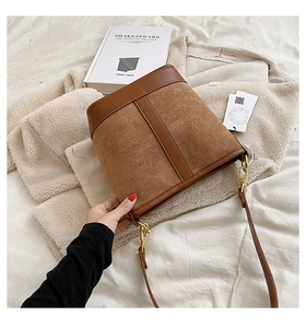 Detail of vintage brown bucket bag with suede texture and gold hardware accents