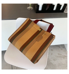 Close-up of a striped canvas tote bag with metal twist lock and bicolor woven handles
