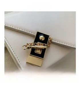 Close-up of golden metal clasp and chain detail on beige leather crossbody bag