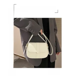 Detailansicht der cremeweißen Satteltasche aus Leder mit goldenen Elementen am Model