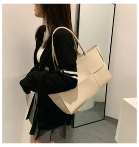 Detail view of cream woven tote bag styled with modern minimalist indoor decor