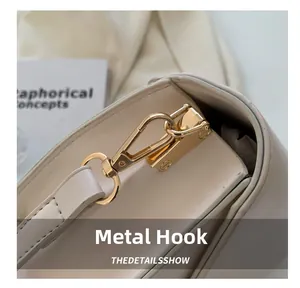 Close-up of premium cream leather bag showing gold hardware hooks and fine stitching