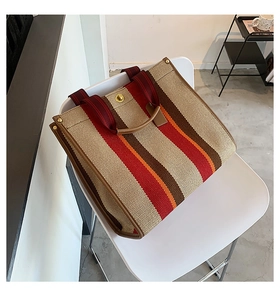 Detail of striped canvas tote bag with brown leather trim and retro vertical stripes