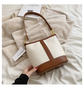 Detailed close-up of a cream and brown contrast bucket bag with gold metal hardware