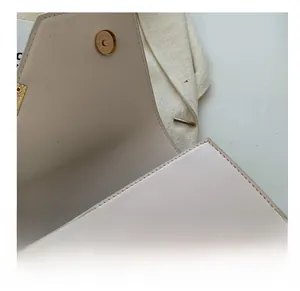 Close-up of bronze magnetic buckle and stitching on cream leather shoulder bag